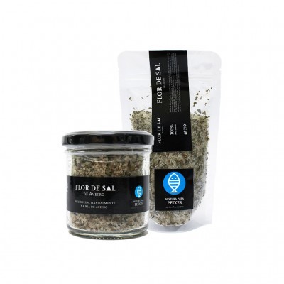 Dois pacotes de flor de sal com ervas, um em frasco de vidro e outro em saco plástico transparente, ambos com rótulos pretos e texto em branco.