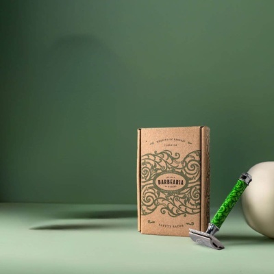 Navalha de barbear com cabo verde decorado e caixa de papelão vintage num fundo verde