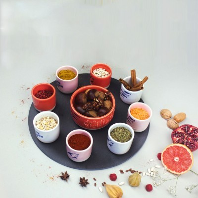 Recipientes com especiarias e ingredientes culinários variados sobre prato preto