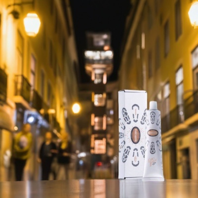 Embalagem e tubo de creme branco com pegadas cinza e texto SALOBREANA em ambiente urbano noturno.