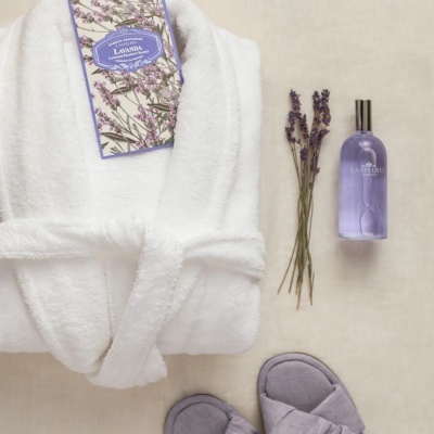 Robe branco, sachê lavanda, frasco roxo, lavanda seca e chinelos cinzentos
