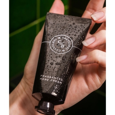 Creme de mãos preto com gotas de água segurado por mão