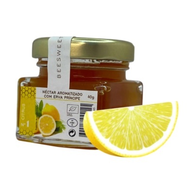 Frasco de néctar aromatizado com erva príncipe ao lado de uma fatia de limão