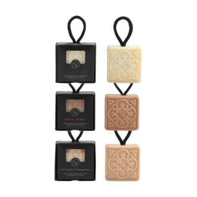 Três sabonetes esfoliantes com cordão preto e suas embalagens pretas com texto das fragrâncias