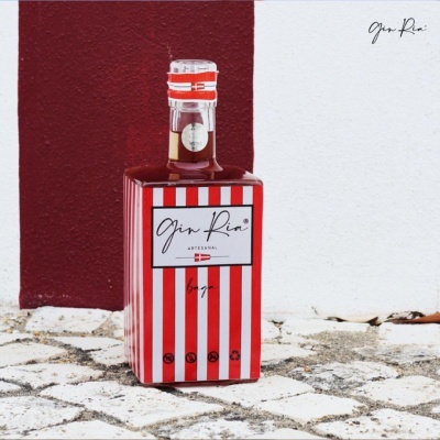 Garrafa quadrada de gin com rótulo vermelho e branco em chão de calçada portuguesa