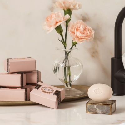 Sabonetes e vaso com flores sobre bancada branca com torneira preta