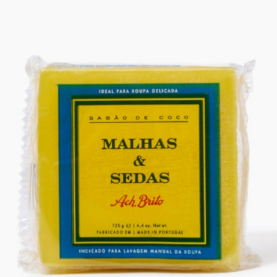 Barra de sabão amarelo com rótulo verde e amarelo, texto preto e vermelho, embalagem plástica transparente