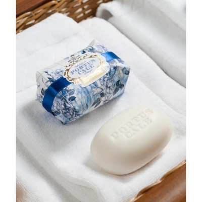 Sabonete Portus Cale com embalagem azul e branca em toalha branca num cesto de vime