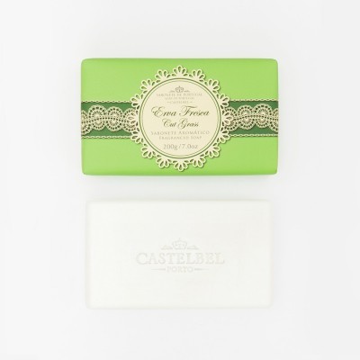 Sabão com embalagem verde e barra de sabão branca com logo em relevo.
