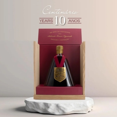Garrafa de gin preta com rótulo dourado numa caixa de madeira e forro vermelho
