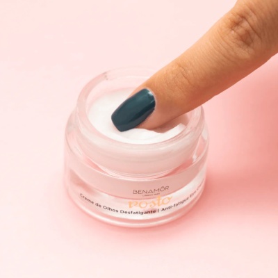 Frasco de creme de olhos com dedo tocando o creme