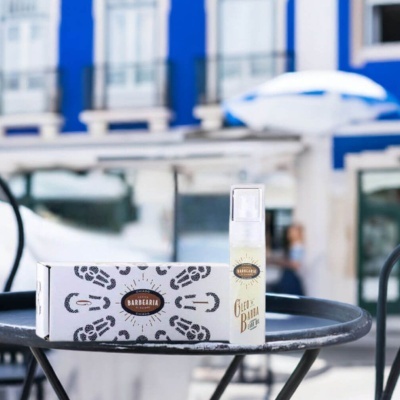 Frasco de óleo para barba com caixa decorada sobre mesa preta