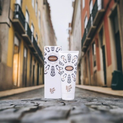 Creme em tubo branco com caixa, padrão preto e dourado, na calçada de rua urbana