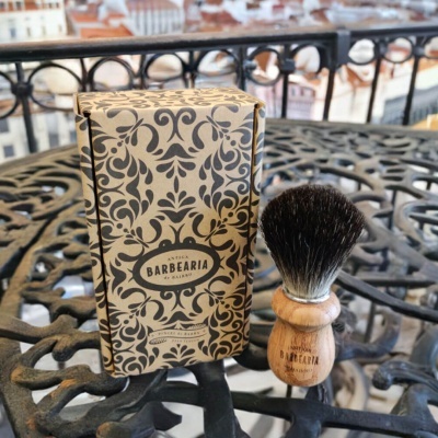 Pincel de barbear com cabo em madeira clara e caixa decorativa ao lado