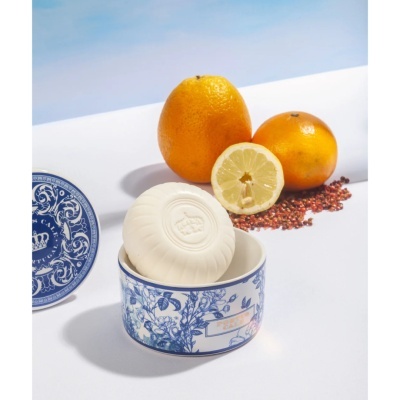 Sabonete branco numa caixa cerâmica azul e branca com citrinos ao fundo