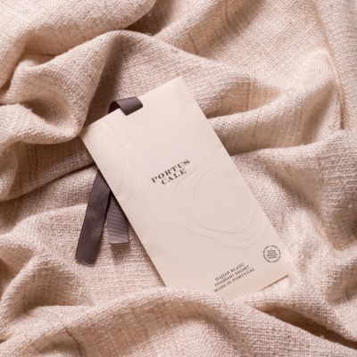 Sache perfumado branco com fita castanha sobre tecido bege texturizado