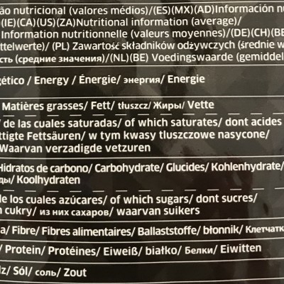 Tabela nutricional multilíngue com valores médios de nutrientes em fundo preto