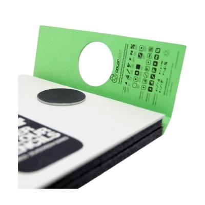 Material com círculos pretos e cartão verde com texto COLORadd e símbolos