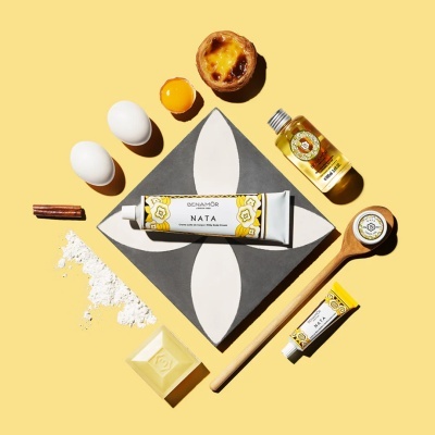 Produtos cosméticos Benamôr com elementos de pastelaria portuguesa sobre fundo amarelo.