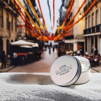 Pote de creme com tampa prateada e texto ANTIGA BARBEARIA DE BAIRRO numa rua decorada ao fundo