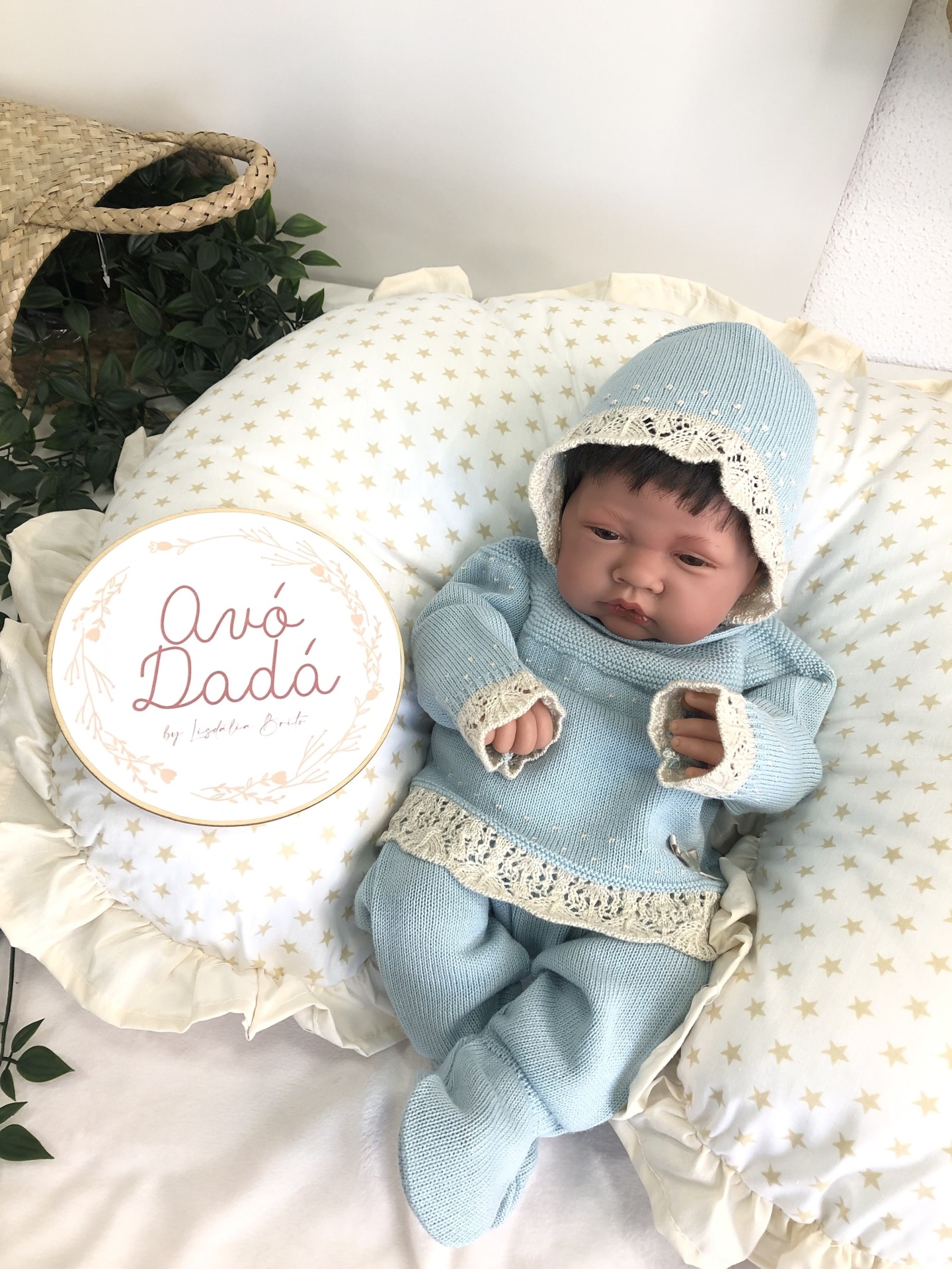 Boneca bebé com roupa azul de malha e almofada com estrelas douradas