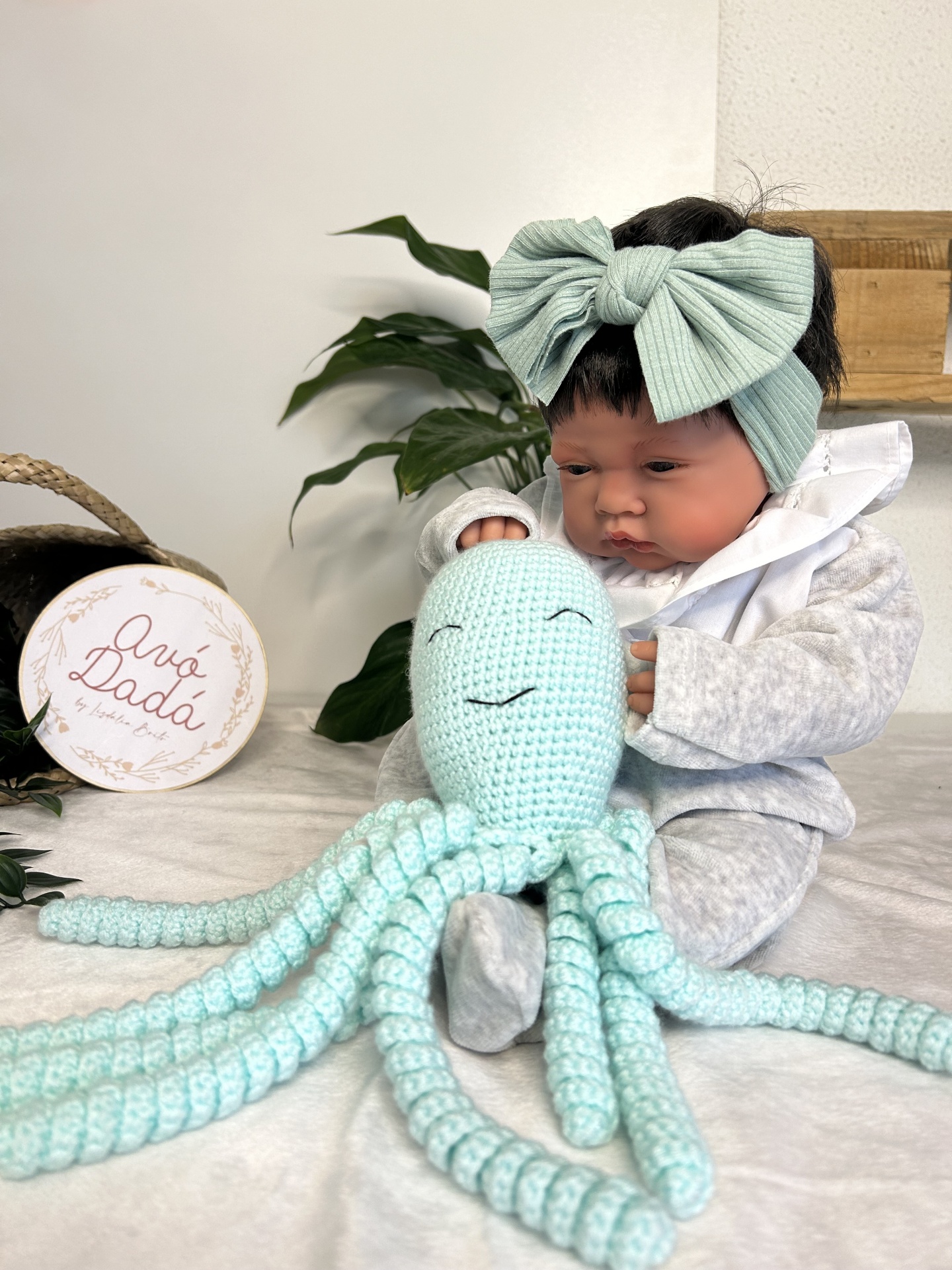 Boneca bebé com laço verde e polvo de crochet verde