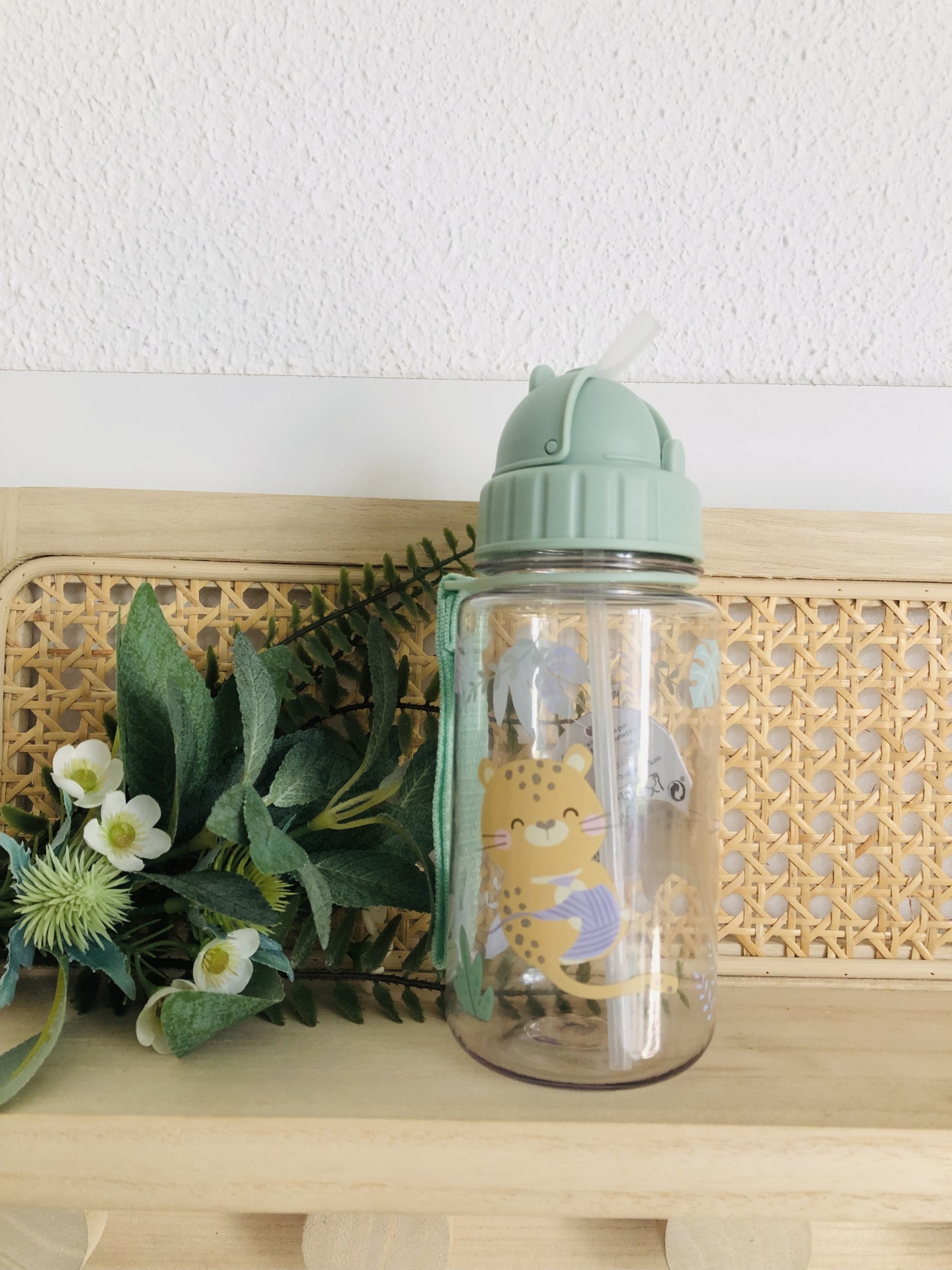 Garrafa de plástico transparente com tampa verde e ilustração de gato.