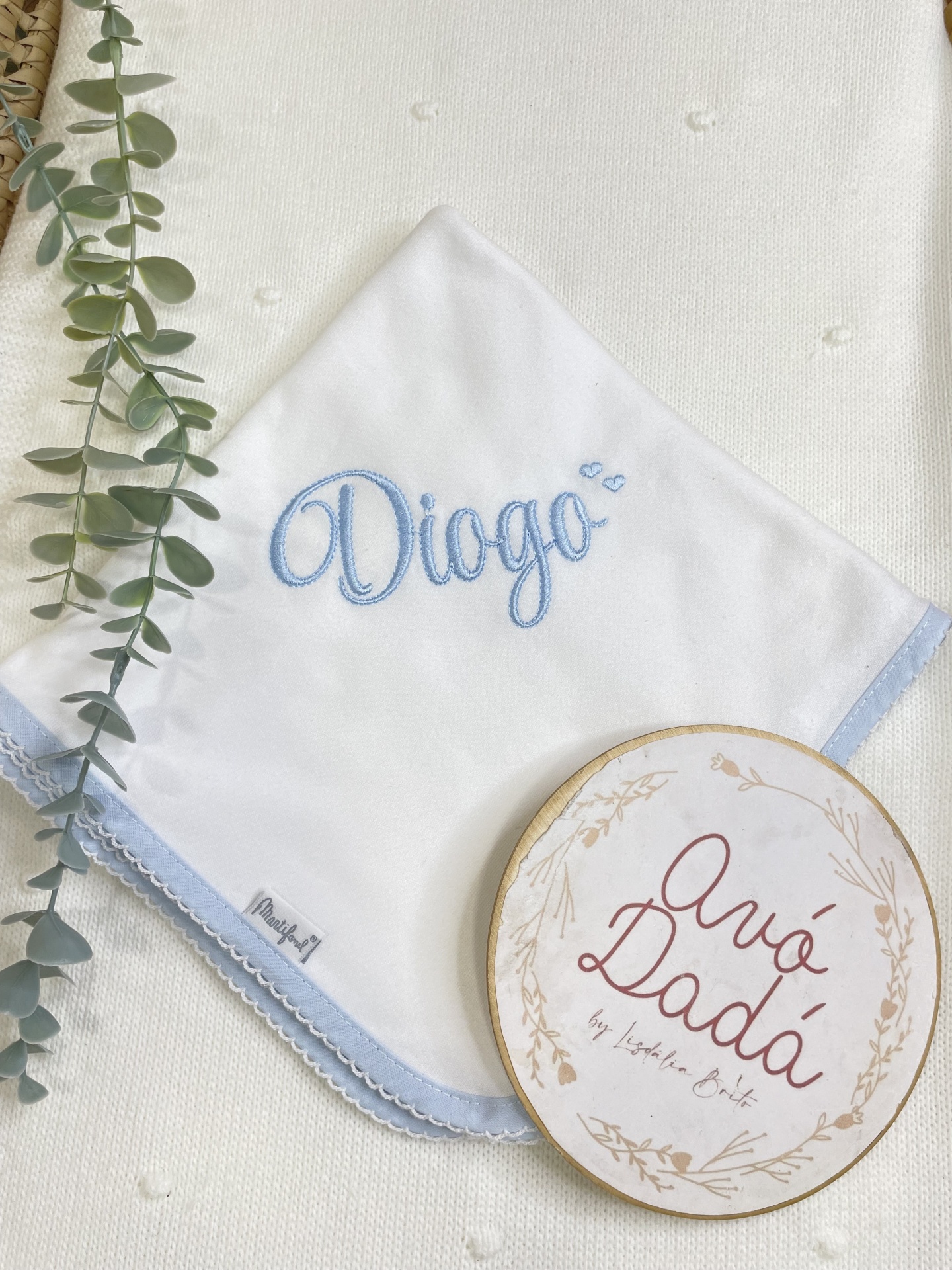 Toalha branca com bordado azul e texto decorativo redondo