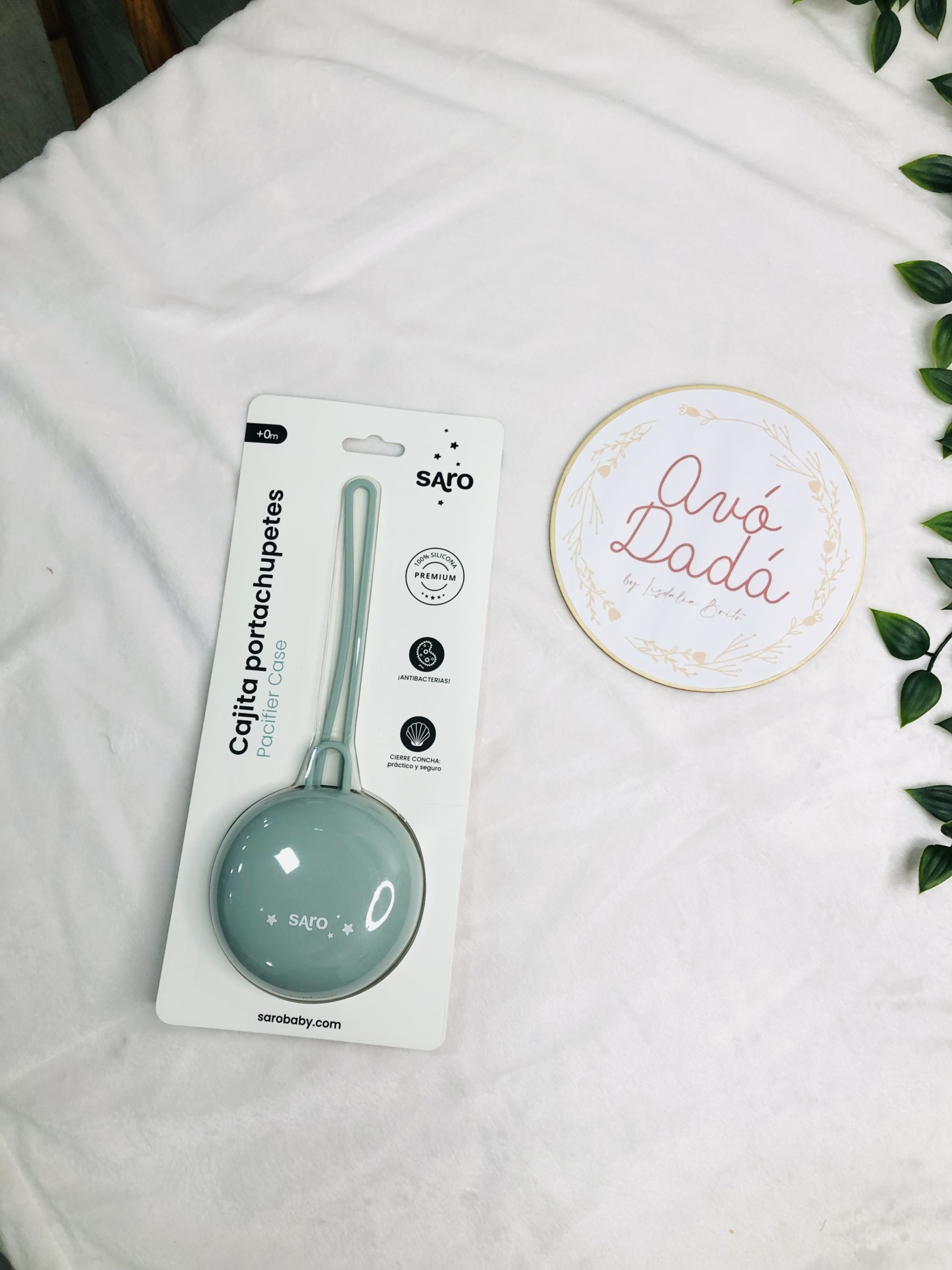 Estojo porta-chupetas verde claro em embalagem branca e placa redonda com texto Avó Dadá sobre tecido branco