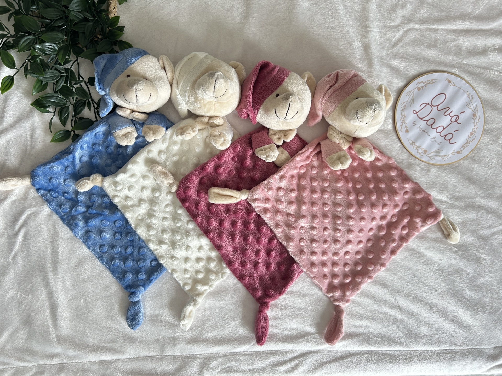 Quatro panos de bebé coloridos com cabeça de animal e padrão bolha sobre cama branca