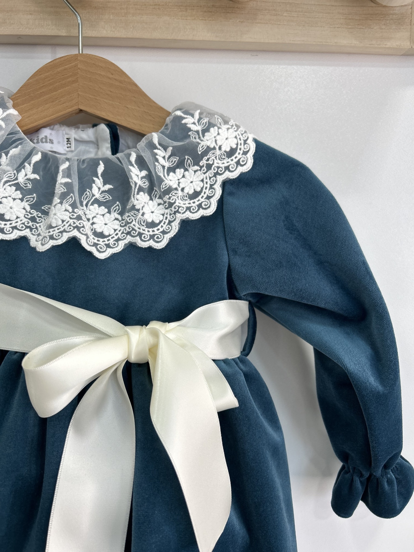 Vestido infantil azul escuro de veludo com gola de renda branca e laço de cetim creme