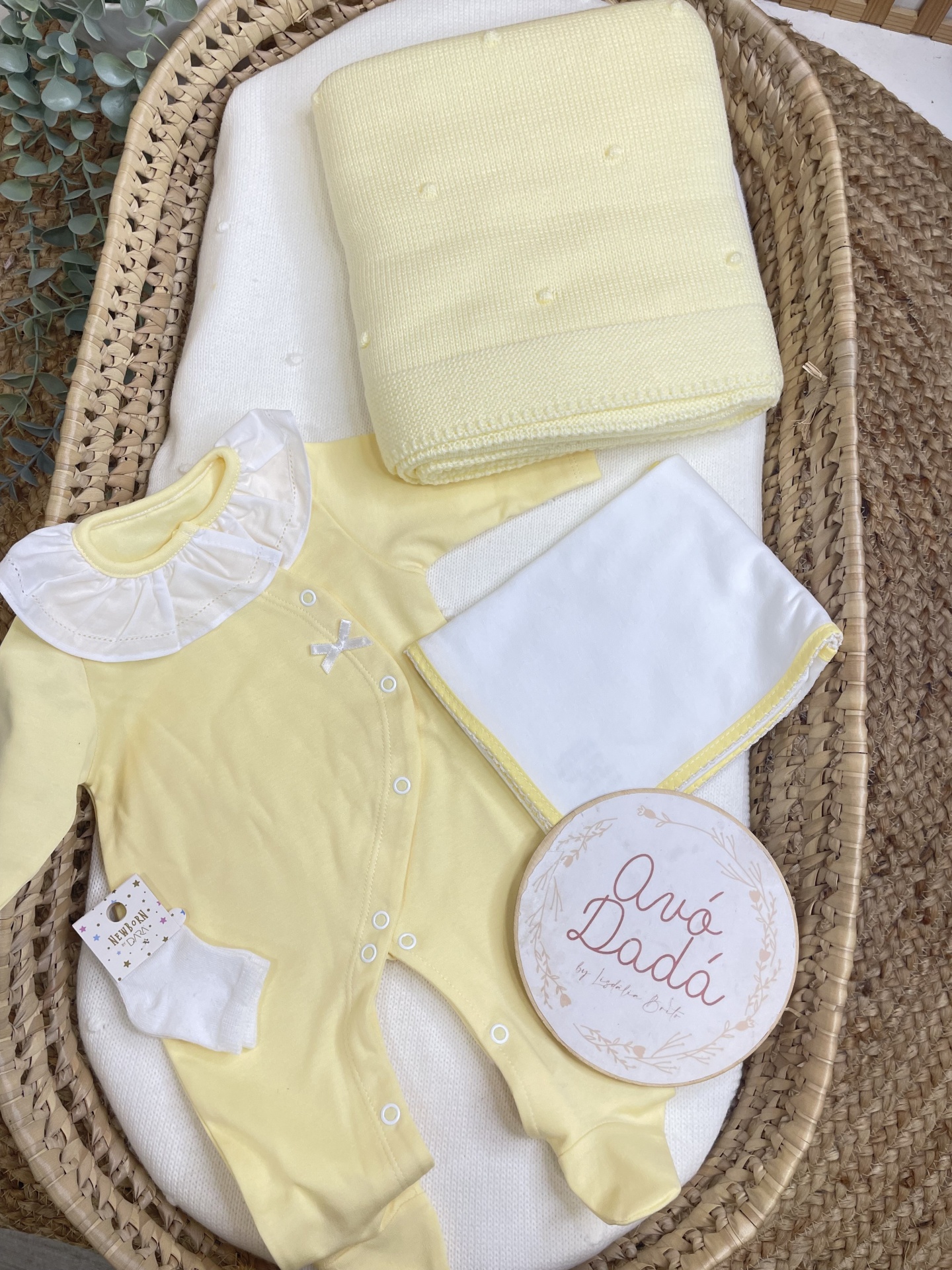 Conjunto de roupa de bebé amarelo com colarinho branco, meias, manta amarela e cesto de palha