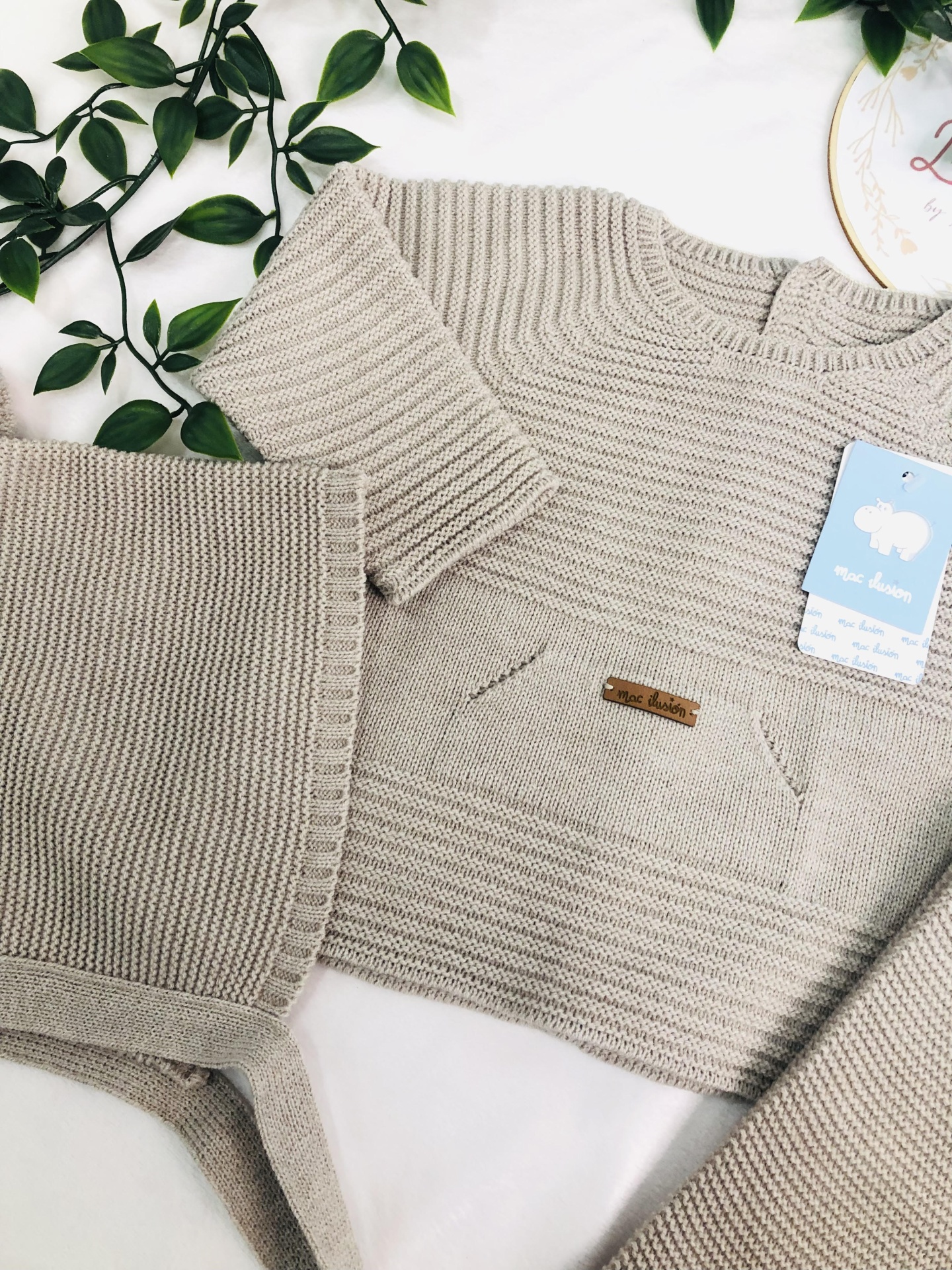 Conjunto de roupa infantil bege em malha com bolso e calças.