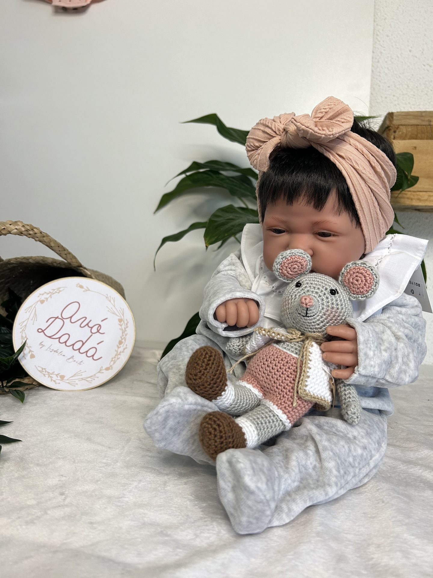 Boneca bebé a segurar rato de tricô e caixa redonda com texto Avó Dadá
