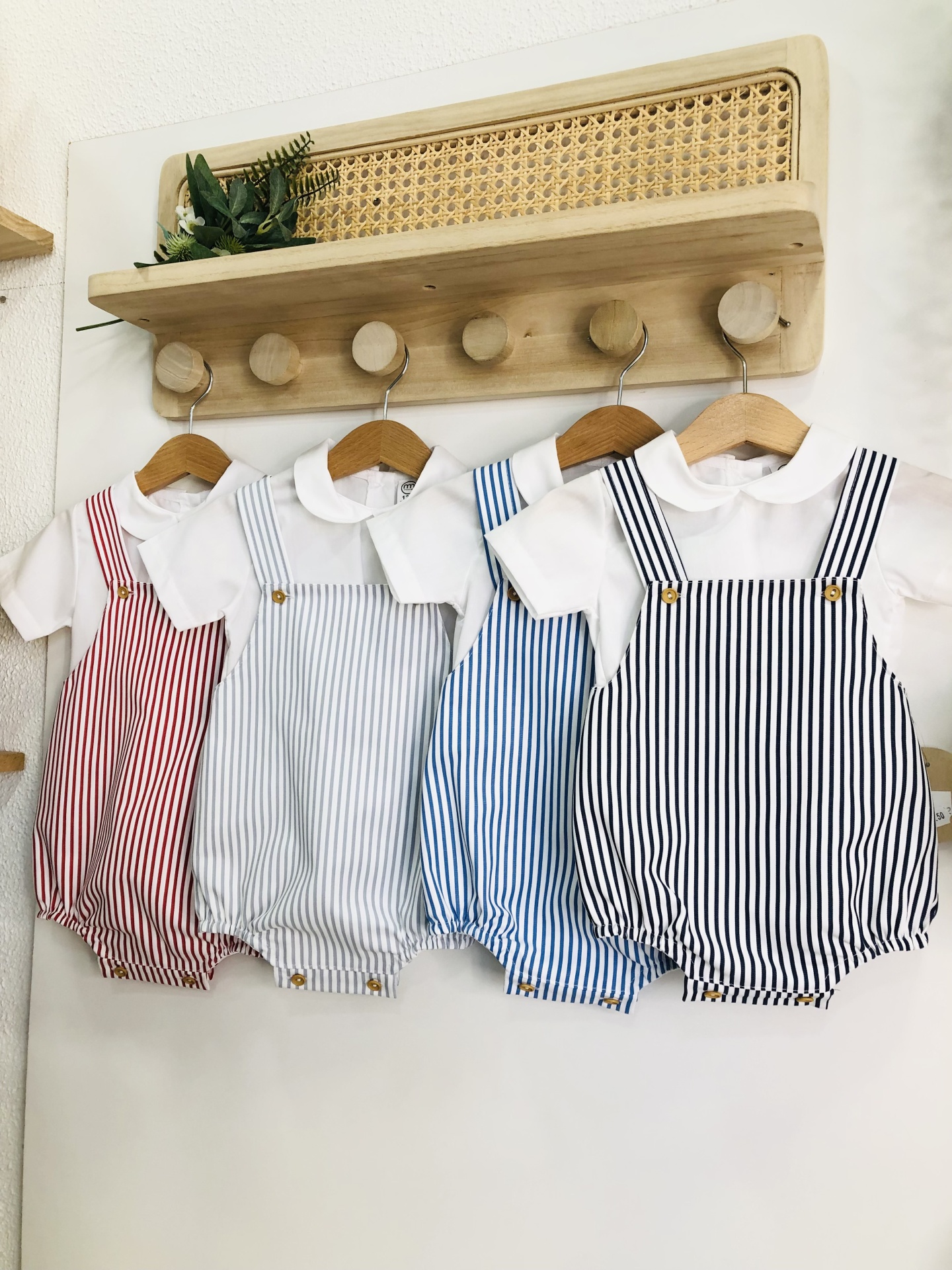 Macacões de bebé às riscas pendurados em cabideiro de parede