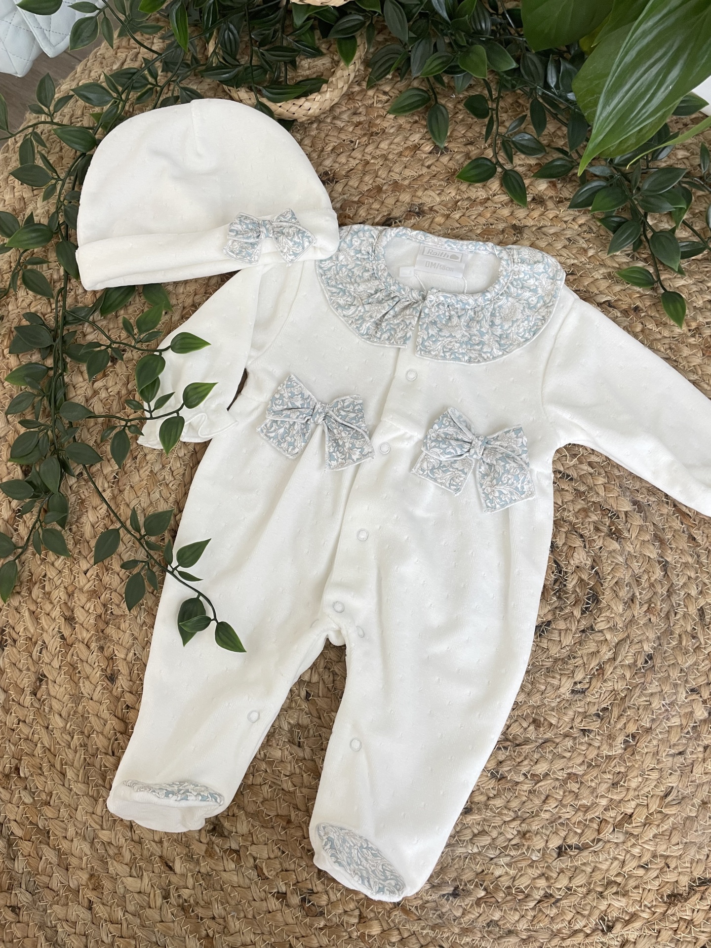 Macacão de bebé branco com detalhes florais azuis e gorro branco com laço