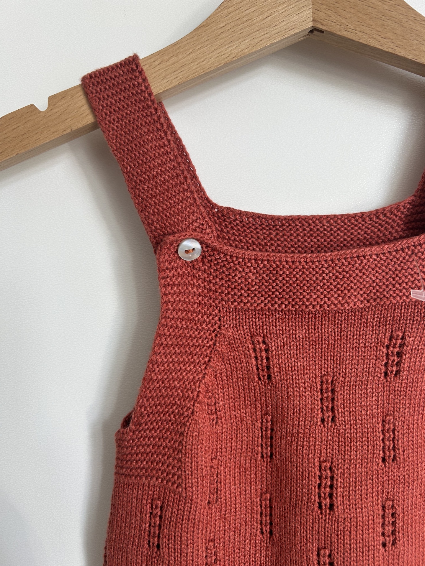 Vestido de malha vermelho tijolo com padrão e alças largas em cabide de madeira
