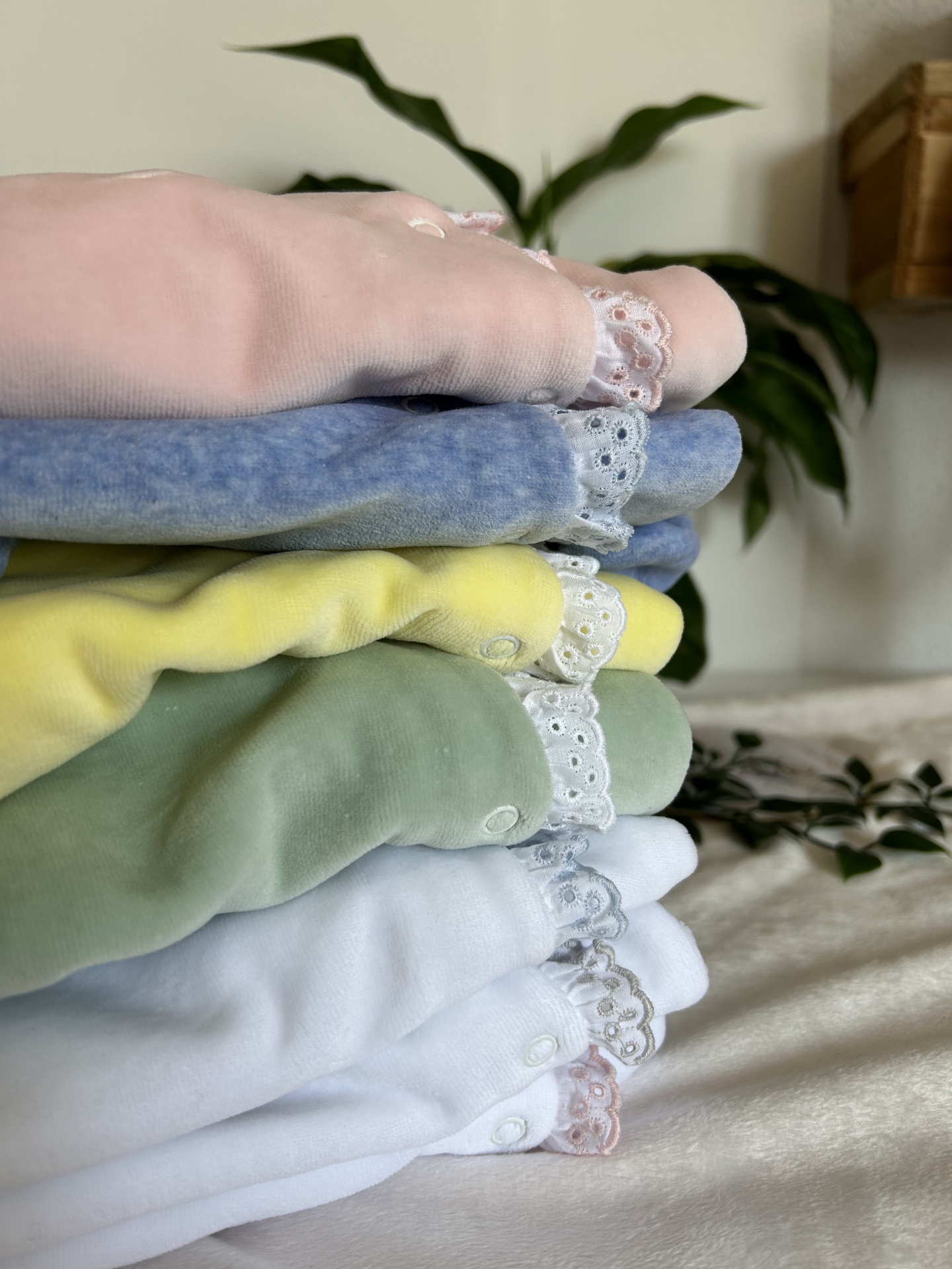 roupa de bebé em várias cores suaves com rendas e botões