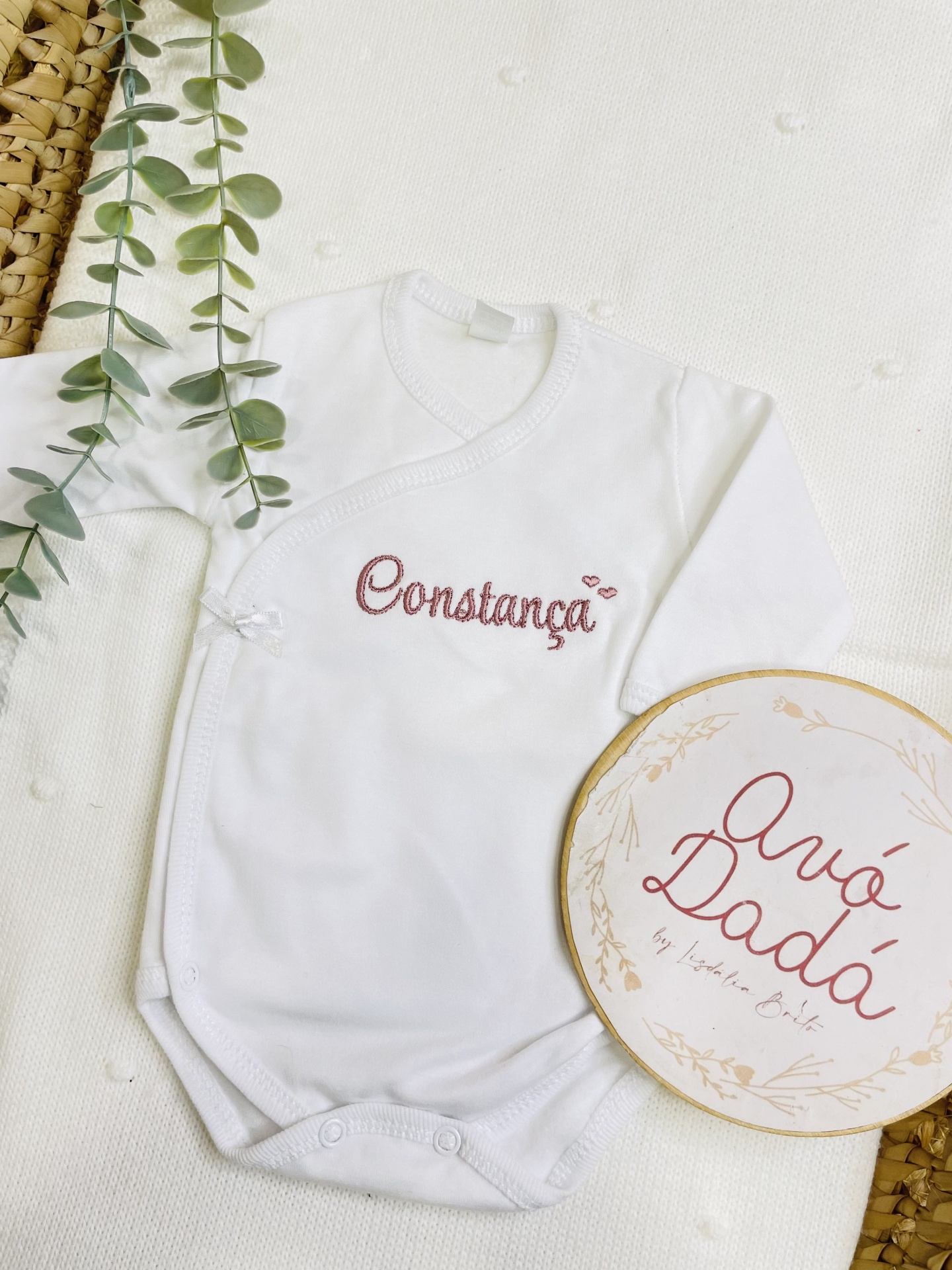 Body branco de bebé com bordado Constança e decoração ao lado