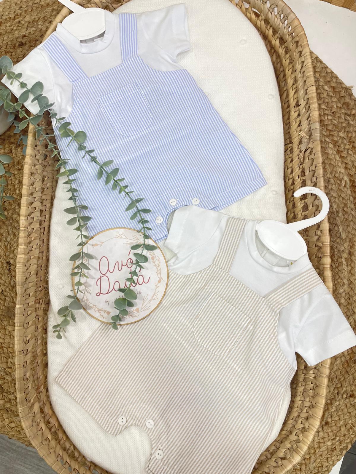 Dois macacões de bebé às riscas azul e bege com t-shirts brancas, expostos num berço de rattan com ramo verde e placa Avó Dada.