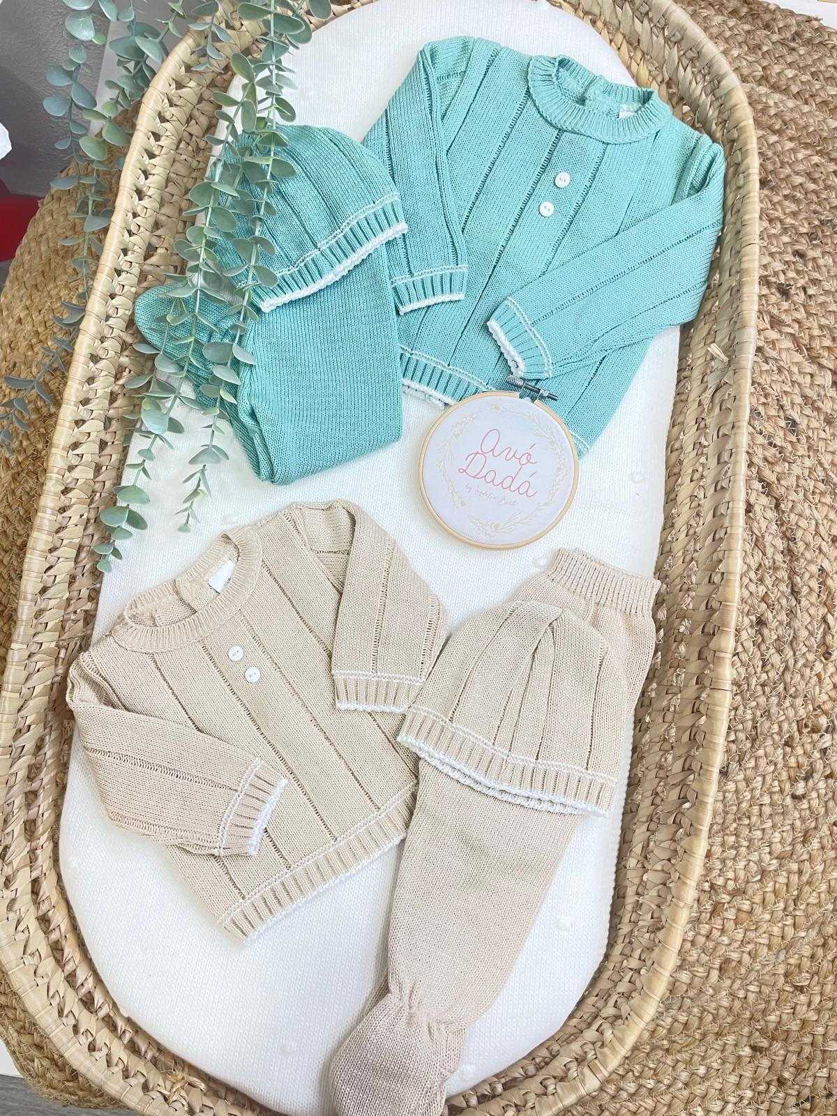 Conjuntos de roupa de bebé em malha azul e bege com detalhes brancos em cesta de verga