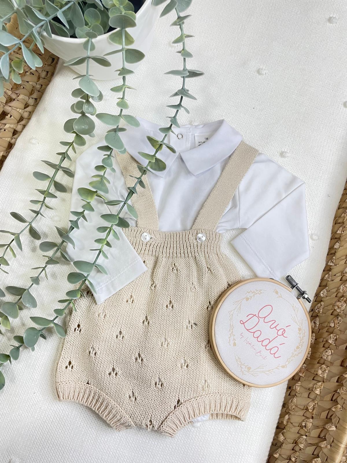 Roupa de bebé branca e bege com planta verde e bastidor bordado