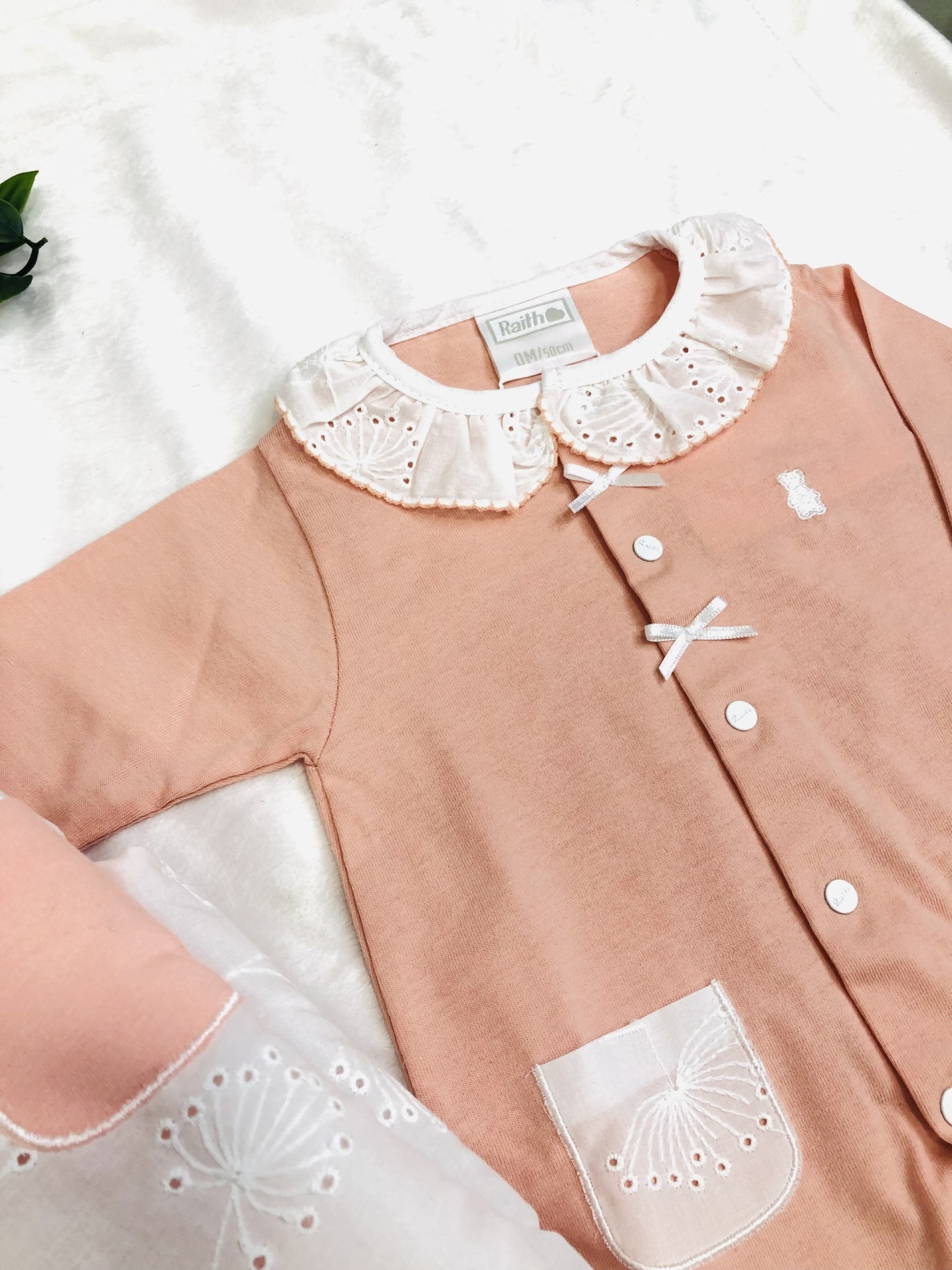 Roupa de bebé rosa com gola branca bordada e botões brancos