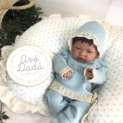 Boneca bebé com roupa azul de malha e almofada com estrelas douradas