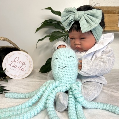 Boneca bebé com laço verde e polvo de crochet verde