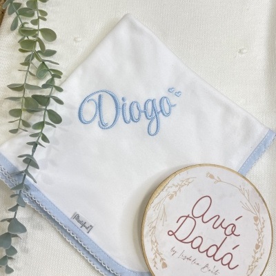 Toalha branca com bordado azul e texto decorativo redondo