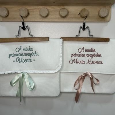 Duas toalhas brancas de bebé com nomes bordados penduradas