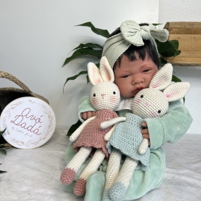 Boneca bebé realista com dois coelhos de crochê coloridos