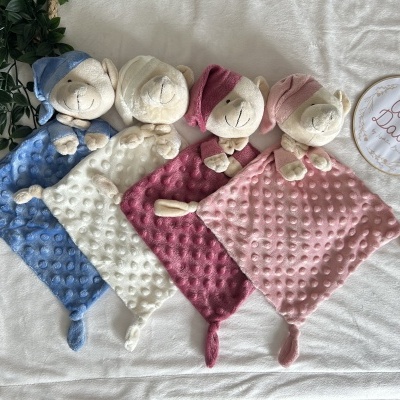 Quatro panos de bebé coloridos com cabeça de animal e padrão bolha sobre cama branca