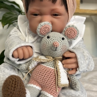 Boneca bebé a segurando rato de croché cinzento, rosa e branco